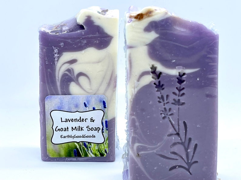 K&ouml;nnte beinhalten: Eine Seife mit Lavendel und Ziegenmilch mit einem Wirbelmuster in Violett- und Wei&szlig;t&ouml;nen. Die Seife hat ein Etikett mit der Aufschrift "Lavender & Goat Milk Soap" und "EarthlyGoodGoods".