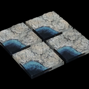 Puede incluir: Cuatro baldosas cuadradas con una superficie texturizada que se asemeja a un paisaje rocoso con una característica de agua azul. Las baldosas están hechas de un material transparente y tienen un aspecto ligeramente esmerilado.