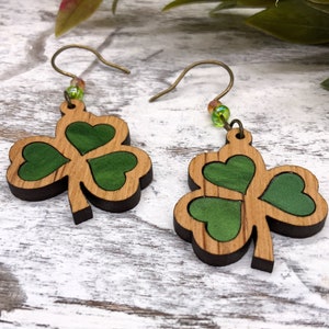 May include: A pair of green shamrock earrings made of wood with a gold-tone wire and green beads.
