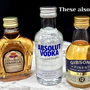 May include: Three miniature liquor bottles, two with gold caps and one with a silver cap. The bottles are labeled "Crown Royal Vanilla", "Absolut Vodka", and "Gibson's Finest Rare Canadian Whisky".