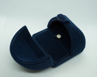 May include: A blue velvet ring box with a single diamond ring inside.