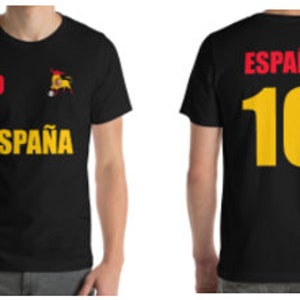 Può includere: Maglietta nera con una grafica di un toro rosso e giallo e il testo "ESPAÑA" sul davanti. La parte posteriore della maglietta ha il numero "10" in giallo.