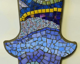 A beautiful blue handmade mosaic hamsa made from stained glass, ceramic tiles,, beads and polymer clay small flowers for home decoration.