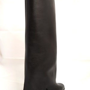 Peut inclure: Bottines noires en cuir montant au genou avec une &eacute;paisse semelle plateforme et un revers pli&eacute;.