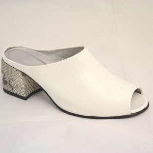 Peut inclure: Mules à talon blanc en cuir avec un talon à motif serpent.