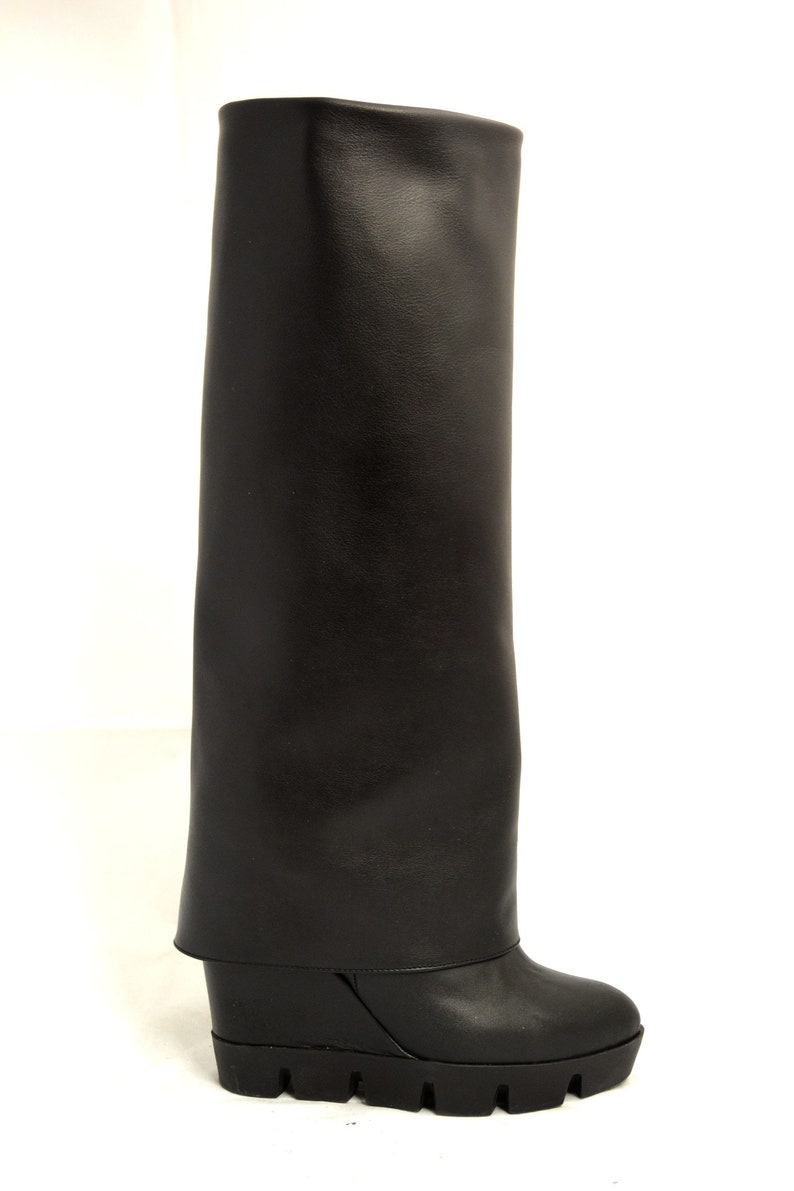 Peut inclure: Bottines noires en cuir &agrave; plateforme compens&eacute;e avec un revers.