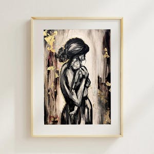 May include: Black and white abstract painting of a person holding a child, framed in a light wood frame. Gold leaf accents the background. The artwork evokes themes of motherhood and tenderness.