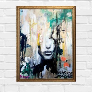 May include: Abstract painting of a face with black, white, green, and orange paint. The face is partially obscured by layers of paint and lines. The painting is framed in gold.