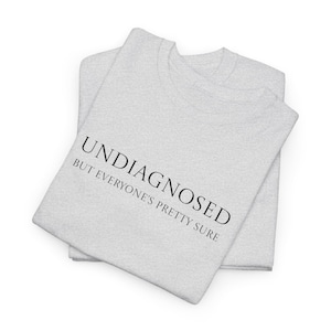 May include: Gray t-shirt with the text "Undiagnosed but everyone's pretty sure" printed on the front.