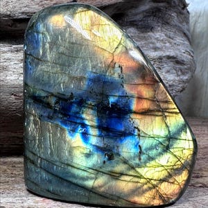 以下が含まれることがあります： 滑らかで丸みを帯びた形の、研磨されたラブラドライトの宝石。石は、青、緑、黄、オレンジの虹色の閃光を伴う鮮やかな色の遊びを示しています。表面には自然な線と模様があり、そのユニークな外観を加えています。