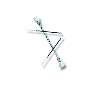 May include: Two baton twirling sticks crossed over each other. One baton features a black and mint green diagonal striped shaft with white fringed ends. The second baton has a solid black shaft with white tips and a light blue end section.