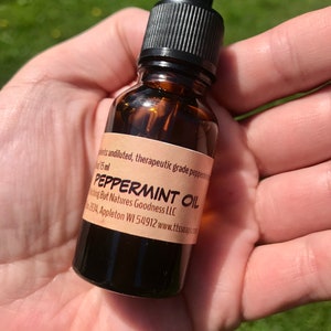 May include: A small brown glass bottle with a black dropper top. The bottle is labeled "Peppermint Oil" and contains 15 ml of oil. The label also includes the text "Nothing But Natures Goodness LLC" and a website address.