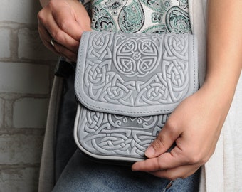 May include: A grey leather crossbody bag with a Celtic knot design.