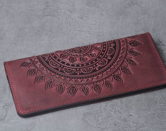 May include: A burgundy leather wallet with a black mandala design embossed on the front.