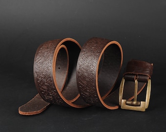 Op de afbeelding: Een bruine leren riem met een reliëfpatroon en een messing gesp.