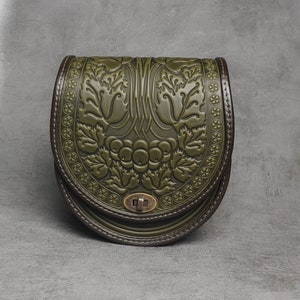 May include: A green leather satchel bag with a floral embossed design. The bag has a flap closure with a metal clasp.