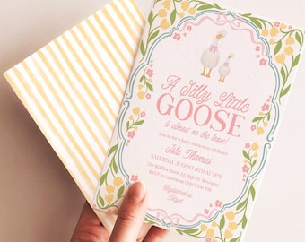 Pode incluir: Um convite para chá de bebê com um design caprichoso. O convite apresenta o texto "A Silly Little Goose" em rosa, com uma ilustração de ganso. O envelope tem listras amarelas e brancas.
