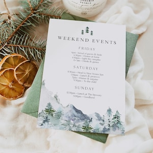 May include: A watercolor illustration of a mountain range with pine trees and a white background. The illustration is on a white card with black text that reads "Weekend Events" and lists a schedule of events for a weekend. The events include arrival of guests, dinner, campfire, drinks, games, lunch, prosecco, dinner, surprise, and goodbyes.