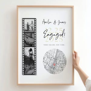 May include: A framed engagement announcement with a light wood frame. The announcement includes a film strip of black and white photos, the names "Amelia & James", the word "Engaged!", the date 2.25.2025, and a map of Times Square, New York.