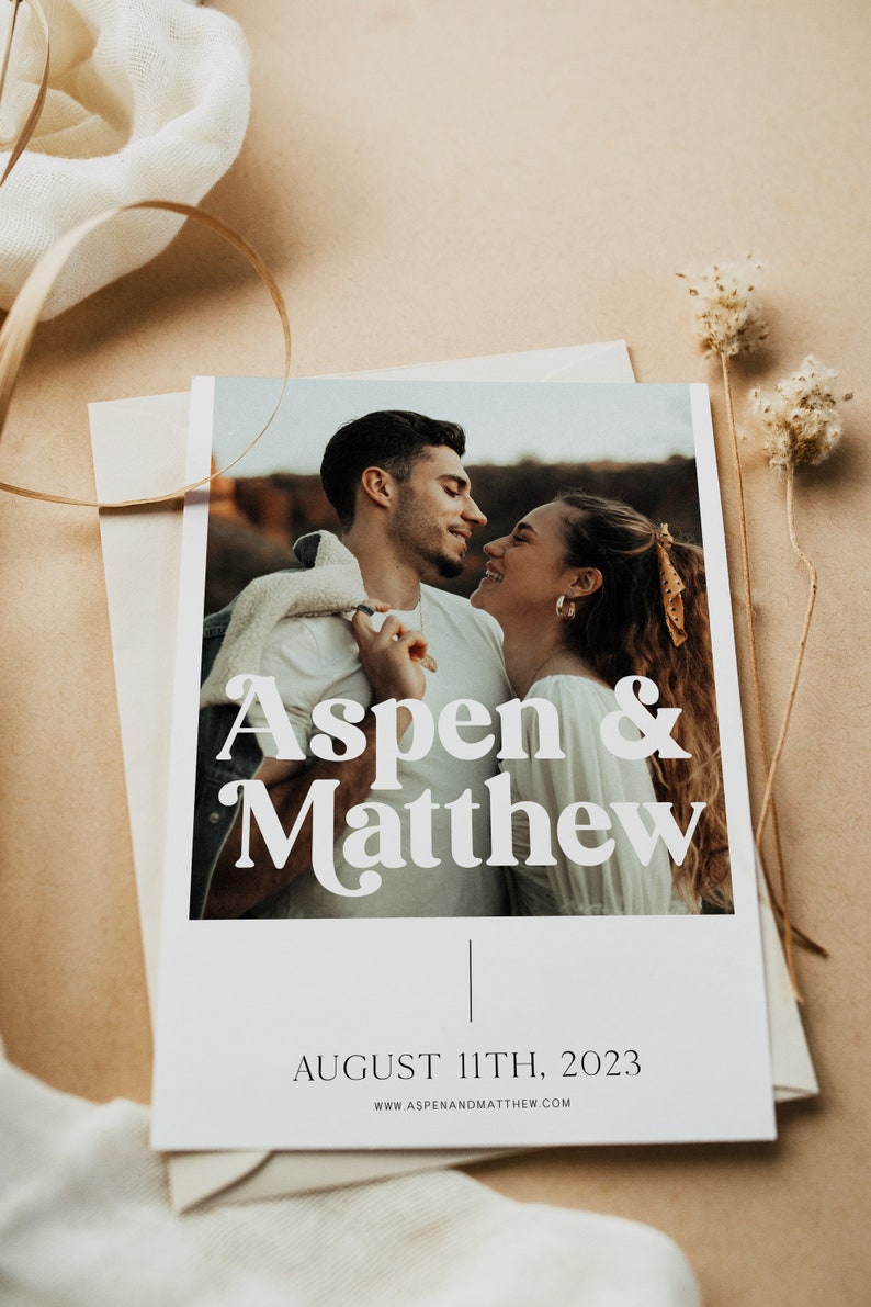 May include: A wedding announcement card with a photo of a couple looking at each other. The card is white with black text that says "Aspen & Matthew" and "August 11th, 2023". The website address "www.aspenandmatthew.com" is printed at the bottom of the card.