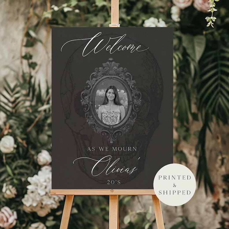 May include: A dark gray welcome sign with a skull graphic in the background. The sign features a framed photo of a woman, with the words "Welcome", "As We Mourn", "Olivia's", and "20's" in elegant script. The sign is on a wooden easel.