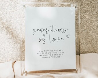 Op de afbeelding: Een helder acryl bord met de woorden "generations of love" in elegant zwart schrift. Daaronder staat de tekst: "Alles wat we zijn en alles wat we hopen te zijn. We zijn het aan onze liefhebbende families verschuldigd."