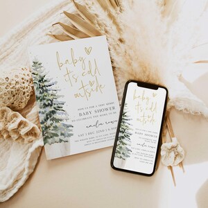 May include: A baby shower invitation with a watercolor illustration of a pine tree with lights. The text reads "baby it's cold outside" in gold lettering. The invitation includes the date, time, and location of the shower.