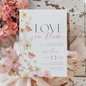 May include: A white bridal shower invitation with a floral design in shades of pink, white, and green. The text reads "LOVE in bloom" and includes details about the event, including the date, time, location, and RSVP information.