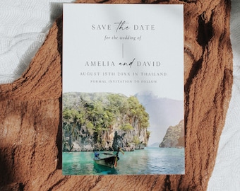 May include: A wedding invitation with the text "SAVE the DATE" and the names "AMELIA and DAVID". The invitation features a scenic photo of a boat on turquoise water surrounded by cliffs and mountains. The date is August 15th, 20XX in Thailand.