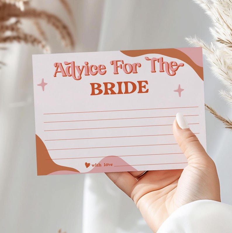 May include: A white card with the text "Advice For The BRIDE" in a retro font, with a wavy design in shades of pink and brown. The card has lines for writing and is held by a hand.