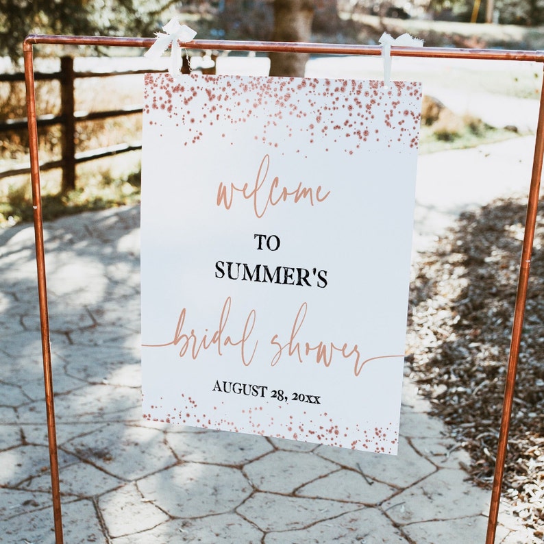 May include: White welcome sign with rose gold glitter confetti. The sign says "Welcome to Summer's Bridal Shower August 28, 20XX".