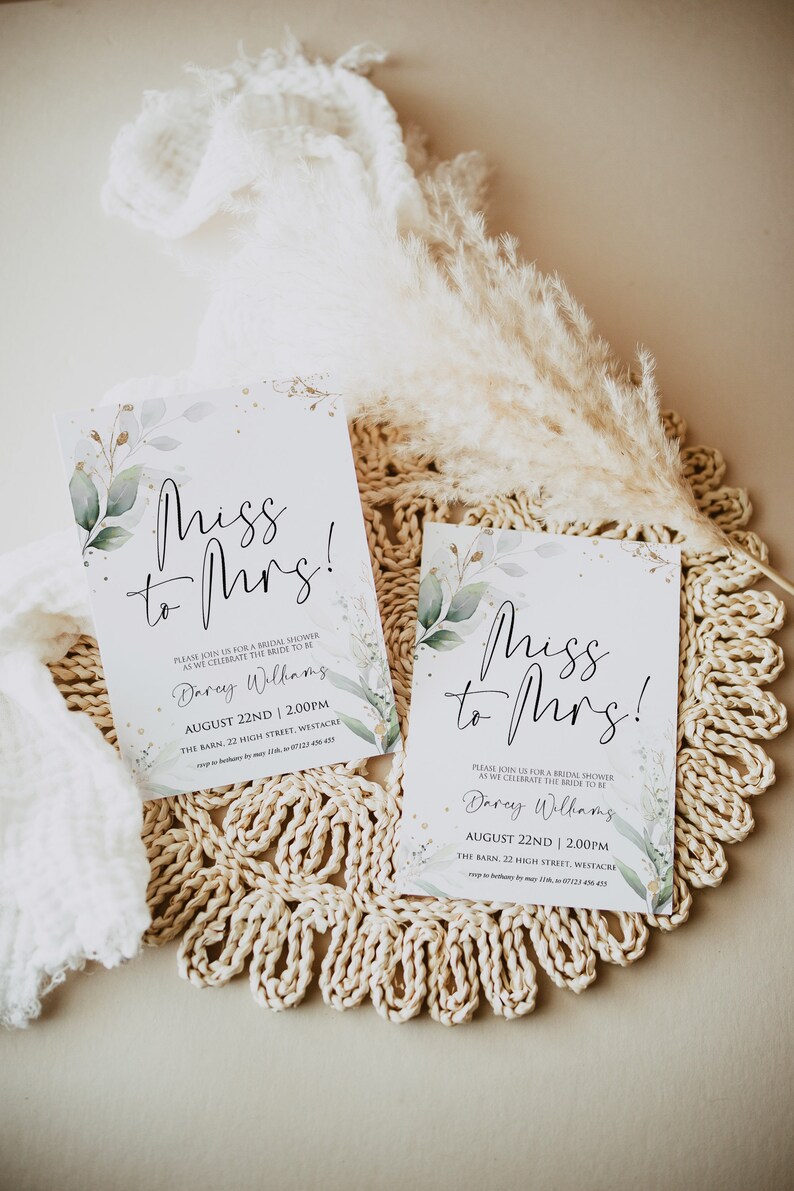 May include: Two white cards with green and gold floral designs and the text "Miss to Mrs!"  The cards are on a woven straw mat. The text on the cards reads: "Please join us for a bridal shower as we celebrate the bride to be Darey Williams August 22nd | 2:00pm The Barn, 22 High Street, Westacre"