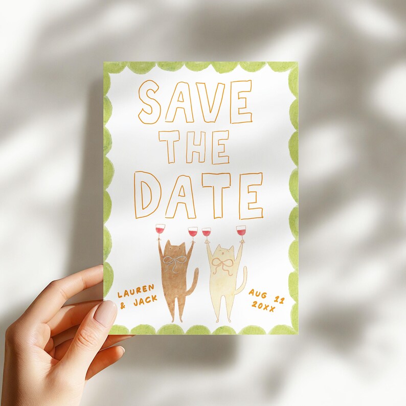 May include: A watercolor "Save the Date" card featuring two cartoon cats toasting with wine glasses. The card has a green scalloped border and includes the names "Lauren & Jack" and the date "Aug 11 20XX".