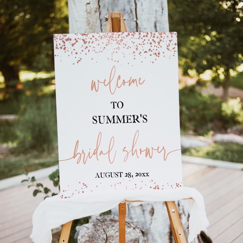 May include: A white welcome sign with a rose gold glitter background. The sign says "Welcome to Summer's Bridal Shower" and "August 28, 20XX".