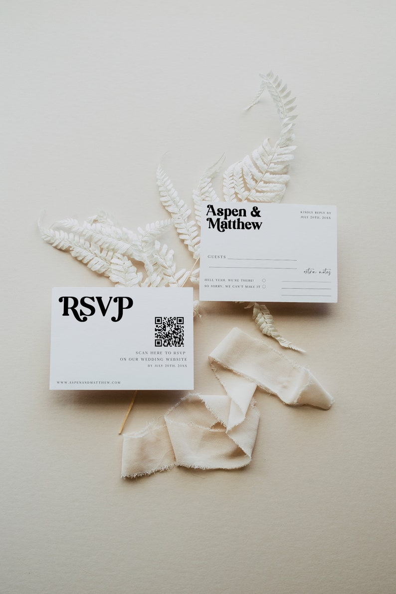 May include: A white RSVP card with a black QR code and the text "SCAN HERE TO RSVP ON OUR WEDDING WEBSITE BY JULY 20TH, 20XX". The card also includes the text "RSVP" in a stylized font and the website address "WWW.ASPENANDMATTHEW.COM".