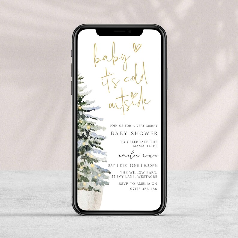 May include: A digital invitation for a baby shower with a watercolor illustration of a snowy pine tree. The text reads "baby it's cold outside" and includes details for the event, such as the date, time, location, and RSVP information.