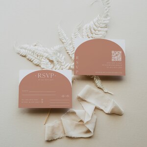 Puede incluir: Dos tarjetas RSVP con fondo melocot&oacute;n y texto blanco. La tarjeta superior tiene un c&oacute;digo QR y el texto "SCAN HERE TO RSVP ON OUR WEDDING WEBSITE BY JULY 20TH 20XX WWW.KAYLAANDOLIVER.COM". La tarjeta inferior tiene el texto "RSVP BY JULY 20TH 20XX" y una secci&oacute;n para que los invitados rellenen sus nombres y RSVP.