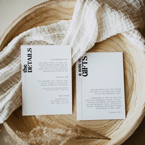 May include: Two white cards with black text on a wooden surface. The first card has the heading "the details" and includes information about accommodation, the ceremony, and the venue. The second card has the heading "a note on gifts" and includes a message about the couple's wedding day and a request for contributions to their wishing well.