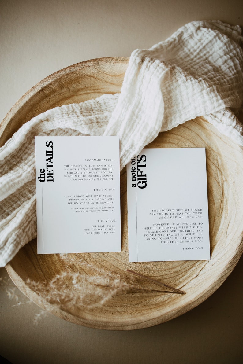 May include: Two white cards with black text on a wooden surface. The first card has the heading "the details" and includes information about accommodation, the ceremony, and the venue. The second card has the heading "a note on gifts" and includes a message about the couple's wedding day and a request for contributions to their wishing well.