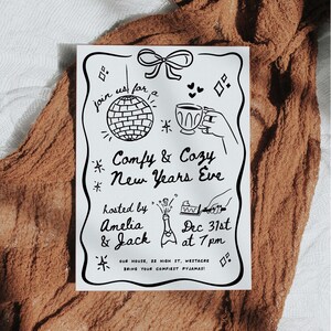 May include: A monochrome invitation for a New Year's Eve party, featuring illustrations of a disco ball, a cup of tea, and a champagne bottle. The text reads "Comfy & Cozy New Years Eve," hosted by Amelia & Jack.