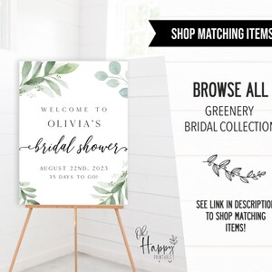 May include: A white sign with green watercolor leaves and the text "Welcome to Olivia's bridal shower August 22nd, 2023 35 days to go!" The sign is on an easel.