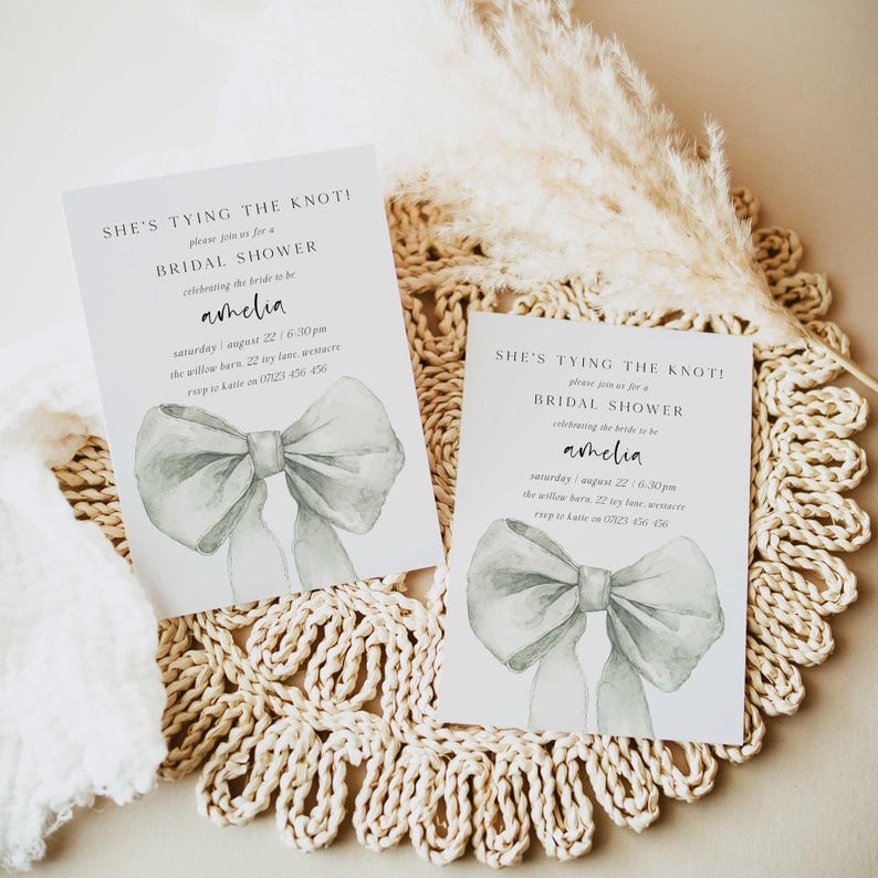 Pu&ograve; includere: Due inviti bianchi per un bridal shower con un'illustrazione ad acquerello di un fiocco grigio. Il testo sugli inviti recita "She's tying the knot!" e include il nome della sposa, la data, l'ora e il luogo.