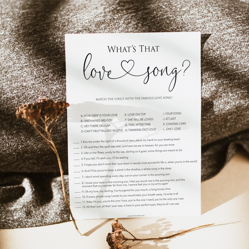 May include: A printable game card with the title "What's That Love Song?" and a list of song titles and lyrics to match. The card has a white background with black text and a heart symbol.