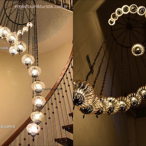May include: A spiral chandelier with 18 glass globes, each with a unique pattern. The chandelier is hanging from a black metal ring and is suspended by chains. The chandelier is 380 cm in height and 96 cm in depth. The text "@karlikturistik" is visible in the image.
