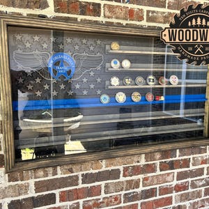 May include: A wooden display case with a glass front, featuring a carved American flag design with stars and stripes. The case includes a blue line and shelves holding various coins. The New Orleans Police Traffic logo is visible.