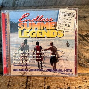 May include: A CD case featuring the album "Endless Summer Legends." The cover art depicts three men on a beach with surfboards. The album includes songs by The Beach Boys, Dick Dale & His Del-Tones, and Jan & Dean.