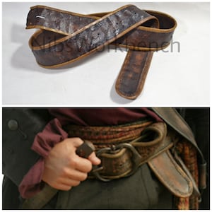 Puede incluir: Un cinturón de cuero marrón con patrones florales en relieve y un borde marrón claro contrastante. El cinturón se muestra en dos imágenes, una plana y la otra con una hebilla de metal.