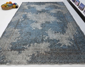 Puede incluir: Una alfombra vintage azul y gris con un patrón floral descolorido. La alfombra tiene un aspecto desgastado y está hecha de lana.