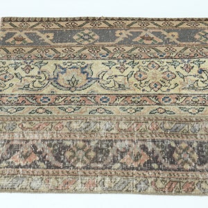 May include: A vintage rug with a beige background and intricate patterns in shades of brown, blue, and pink. The rug has a worn and faded look, giving it a rustic and antique feel.