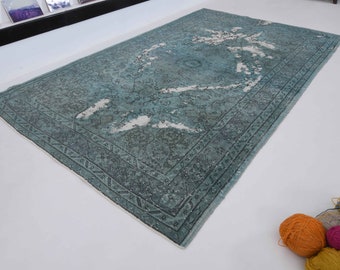 Puede incluir: Una alfombra vintage azul turquesa con un patrón blanco descolorido y un borde azul oscuro. La alfombra tiene un aspecto desgastado y está hecha de lana.